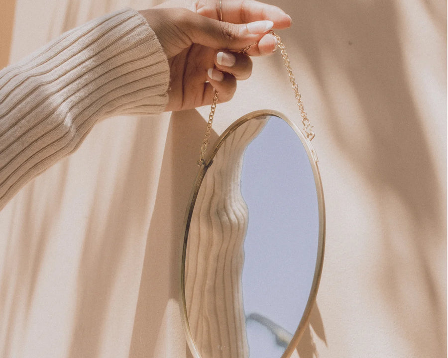 Main de femme tenant un miroir pour se regarder car le stress lui a fait prendre du poids.